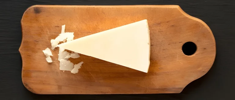 Pecorino Romano cheese, a hard, sheep's milk cheese with a nutty flavor, displayed on a wooden cutting board.