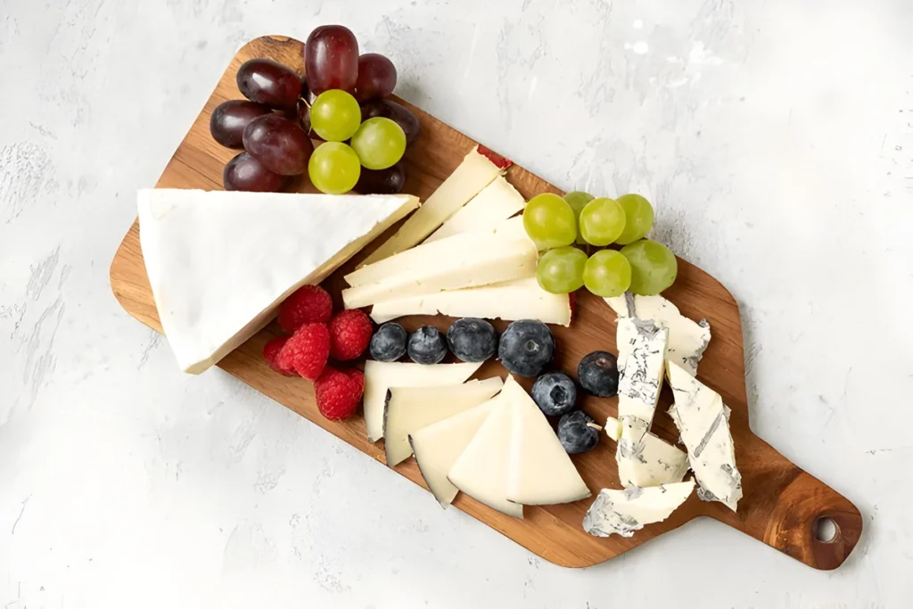 cheese board featuring Parmesan and Pecorino cheese, accompanied by fresh fruits and nuts.